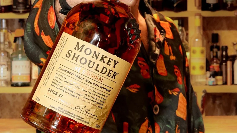 A bartender holds out a bottle of Monkey Shoulder scotch