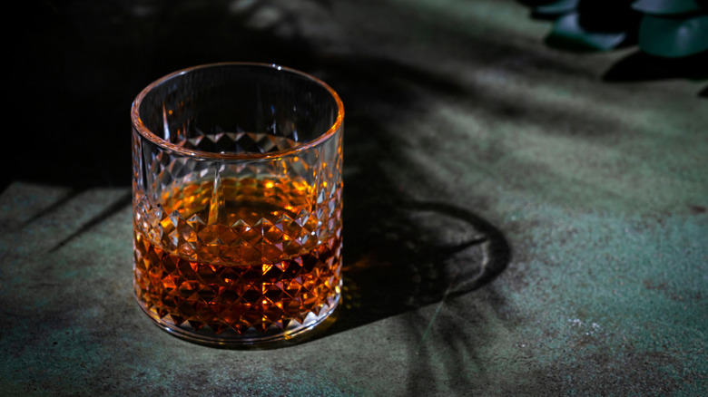 a crystal glass of whiskey against a dark background