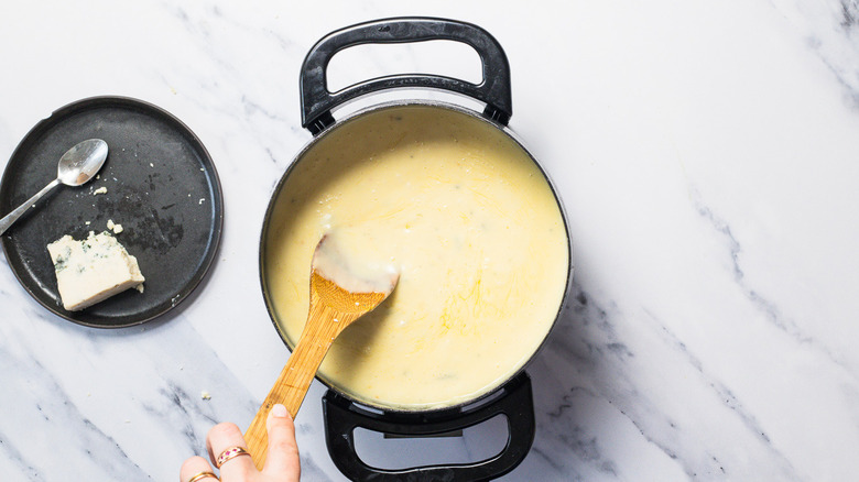 Stirrind gorgonzola into fondue.