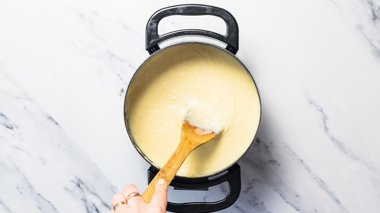 Stirrind fondue in a pot.