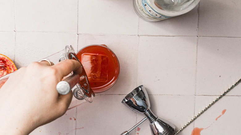 Pouring cocktail into glass over ice