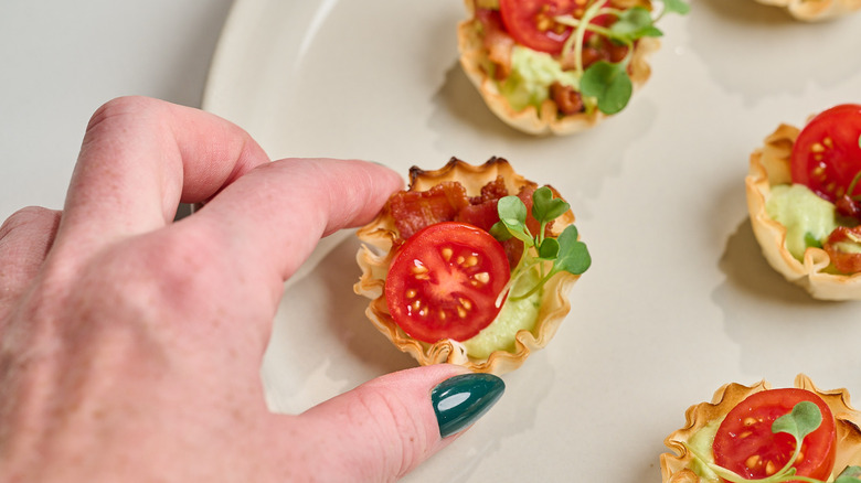 handing picking up a phyllo cup from a platter