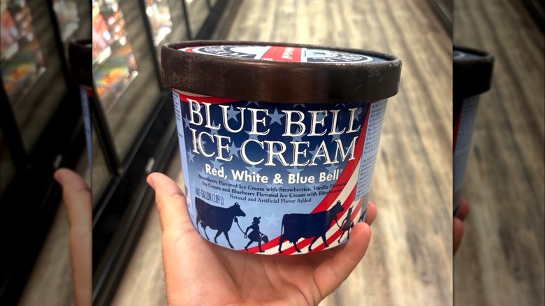 Hand holding container of Blue Bell Blue Bell's Red, White & Blue Bell ice cream