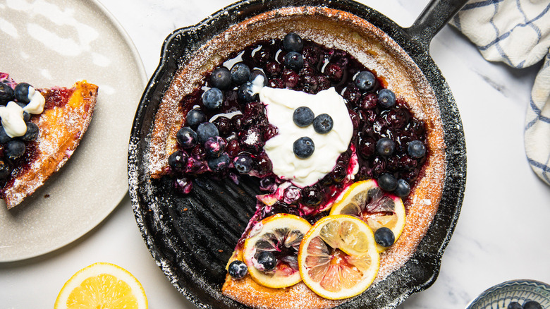 Blueberry lemon Dutch baby pancake in cast iron pan with slice taken out.