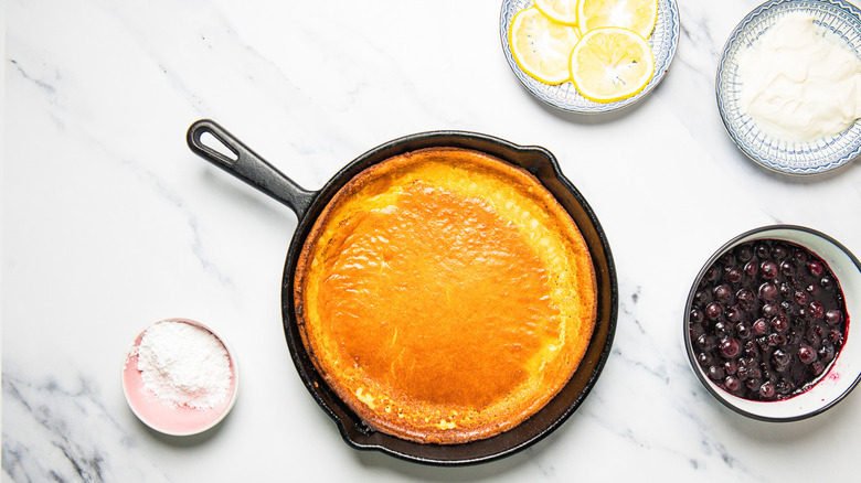 Dutch baby pancake in cast iron pan with all the toppings around.