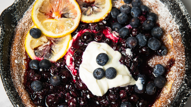 Close up on toppings on blueberry lemon dutch baby pancake in cast iron pan.