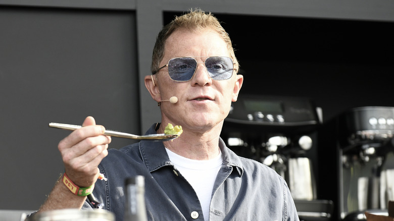 Bobby Flay cooking at event in sunglasses and a grey shirt