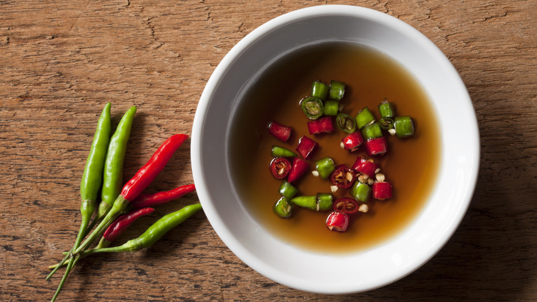 Sliced Thai chili peppers sitting in a bowl of fish sauce