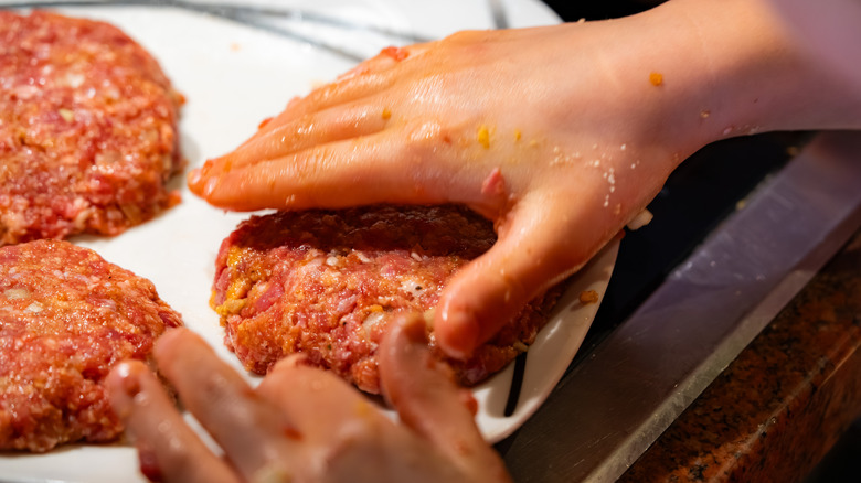 Person shaping burgers on a plate