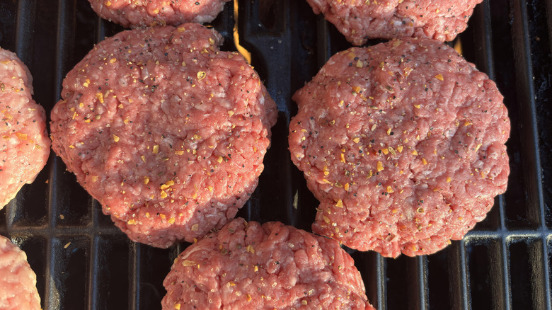 Top view of seasoned burger patties assembled on a grill
