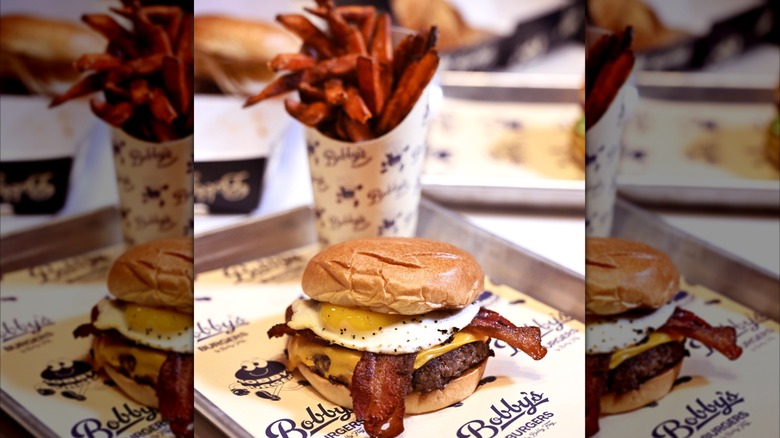 Brunch burger on a platter with sweet potato fries in the background