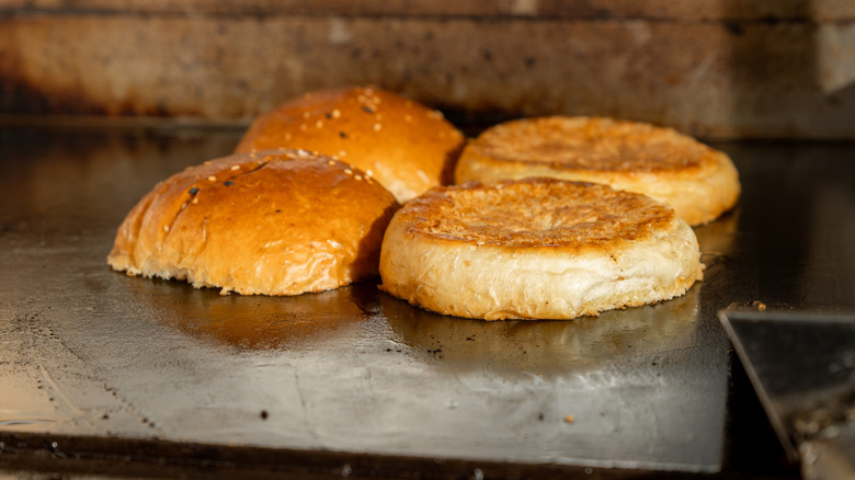 Toasting two classic burger buns on a flat-top griddle