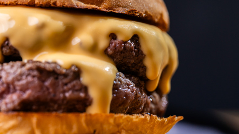 Close up of melted cheese dripping down double cheeseburger