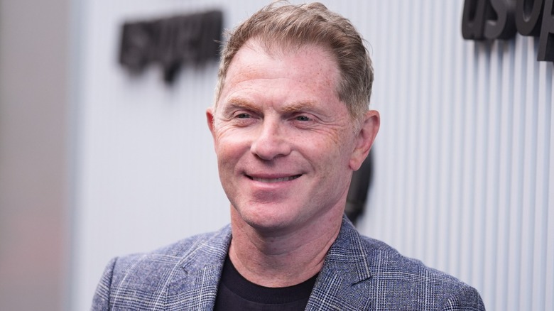 Bobby Flay smiling in a jacket and black t shirt