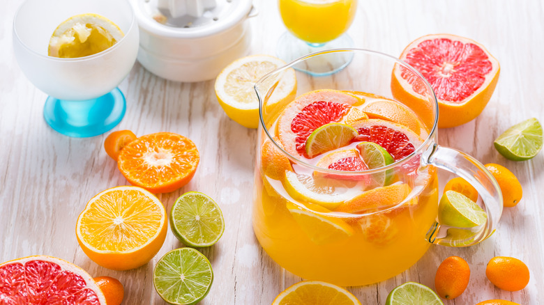 different citrus fruits cut in half with jug