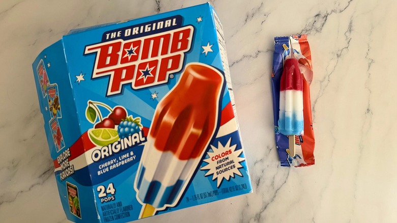 Box of Original Bomb Pops next to opened Bomb Pop on marble surface