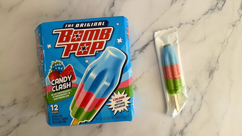 Box of Candy Clash Bomb Pops next to opened Bomb Pop on marble surface