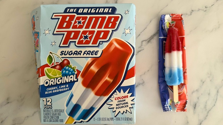 Box of Sugar Free Original Bomb Pops next to opened Bomb Pop on marble surface