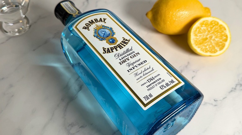 Bottle of Bombay Sapphire laying down on table, lemons behind