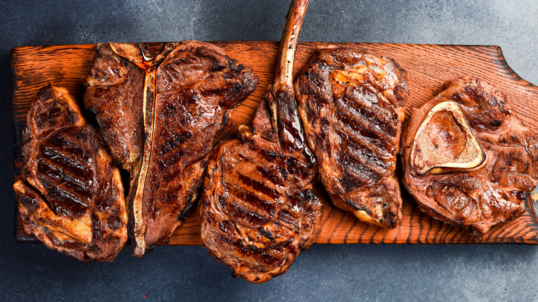 Variety of grilled steaks on a cutting board, including boneless and bone-in ribeyes