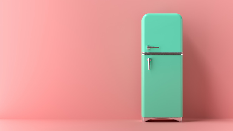 Turquoise refrigerator against pink background