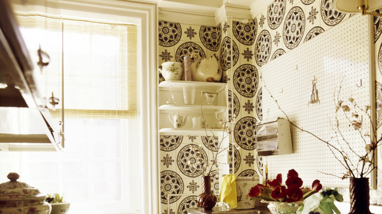 1970s kitchen with white shelves, plants, and patterned wallpaper