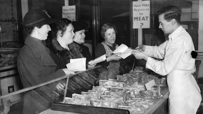 Foodies cashing in their ration books at a meat counter during World War II
