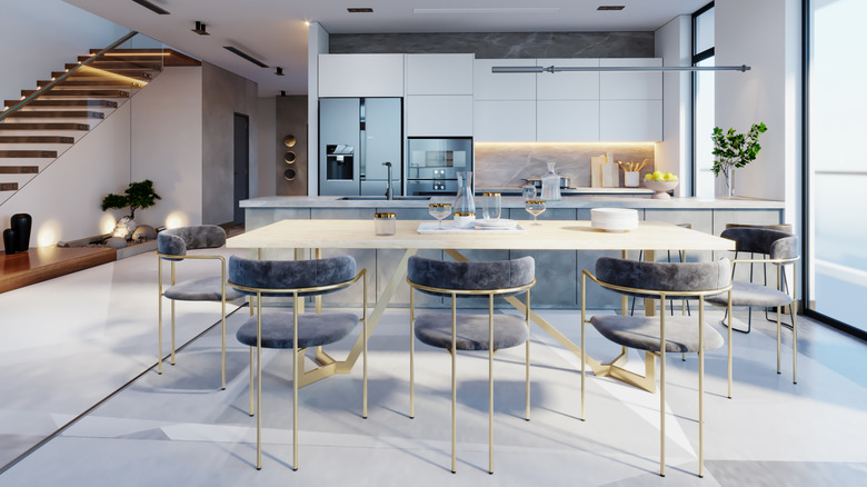 A very modern, white kitchen and dining area in a home with an open floor plan