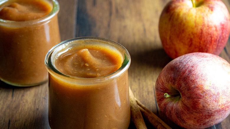 apple butter in a glass container next to an apple