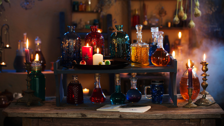 a collection of bottles on a wooden table alongside burning candles