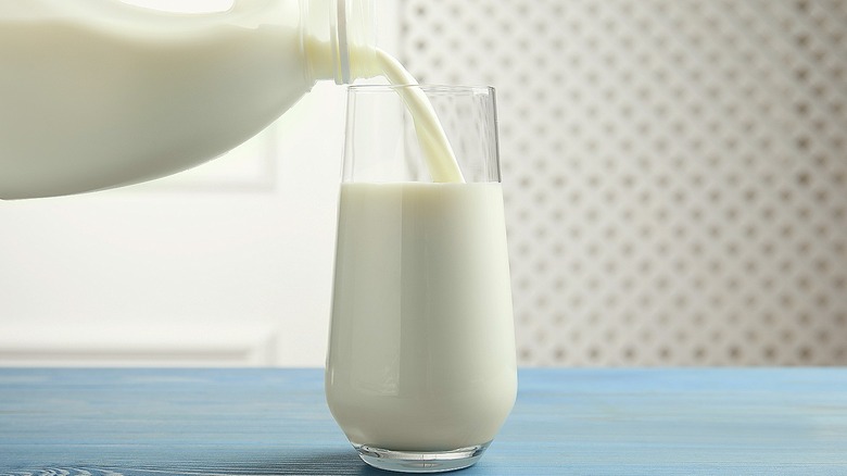 milk being poured into a glass from a gallon jug