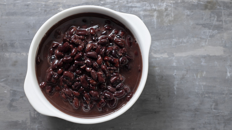 cooked black beans in liquid in a white bowl against gray surface