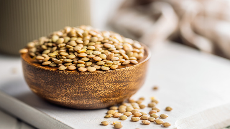 uncooked green lentils in a wooden bowl