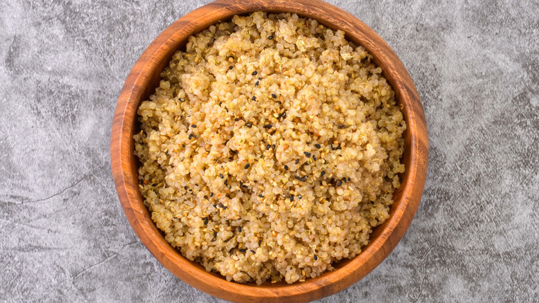 wooden bowl of quinoa against a gray background