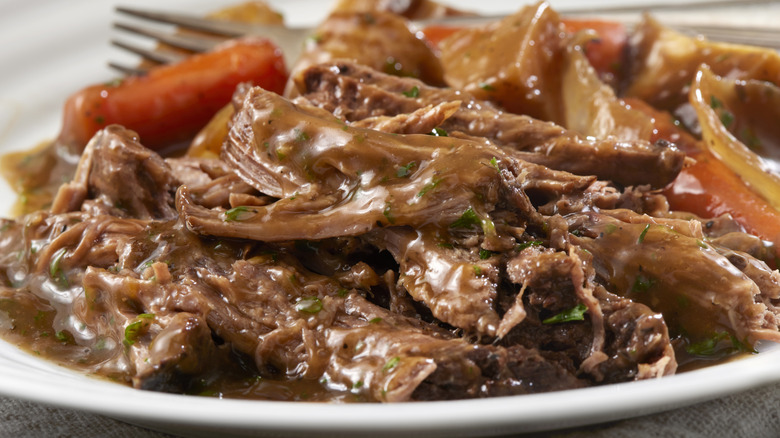 Slow cooker pot roast on a white plate with carrots