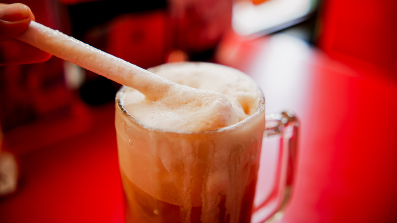 Foam-topped ice cream shake soda with a straw.