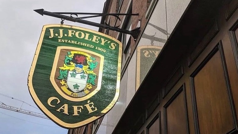 ground up shot of the wooden, green and gold painted J.J. Foley's Cafe sign and coat of arms