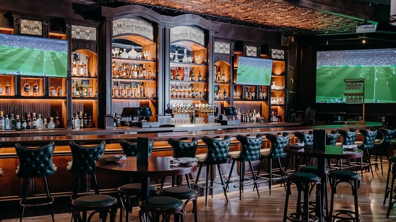 dark wood bar with leather seating and TVs showing a soccer game