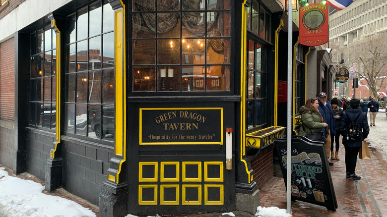 Image of a corner tavern, Green Dragon Tavern, with paned glass windows and a black and yellow motif