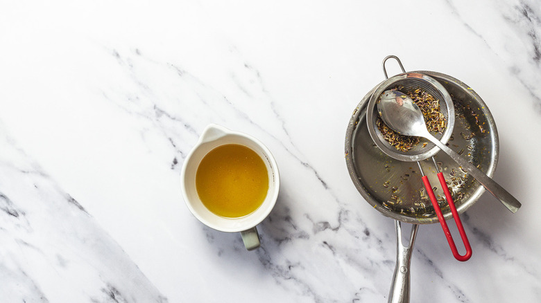 Cup with lavender sryup alongside strained lavender buds.