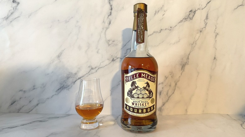 Bottle of Belle Meade bourbon next to glencairn of bourbon on marble background