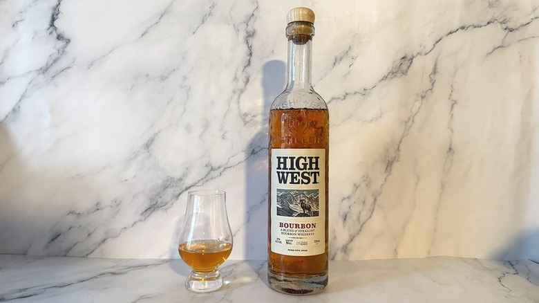 Bottle of High West bourbon next to glencairn of bourbon on marble background