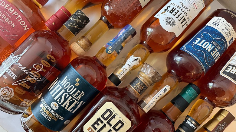 Top-down shot of several bourbon bottles lined up on marble surface