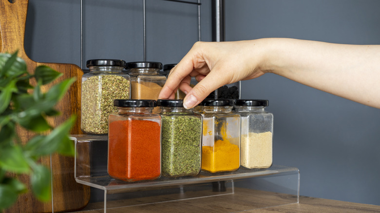Person selecting jars of seasonings.