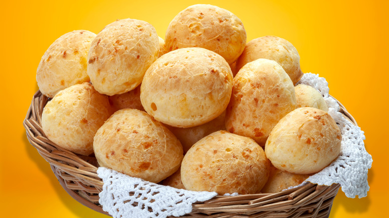 Basket of pão de queijo in front of a yellow-orange background