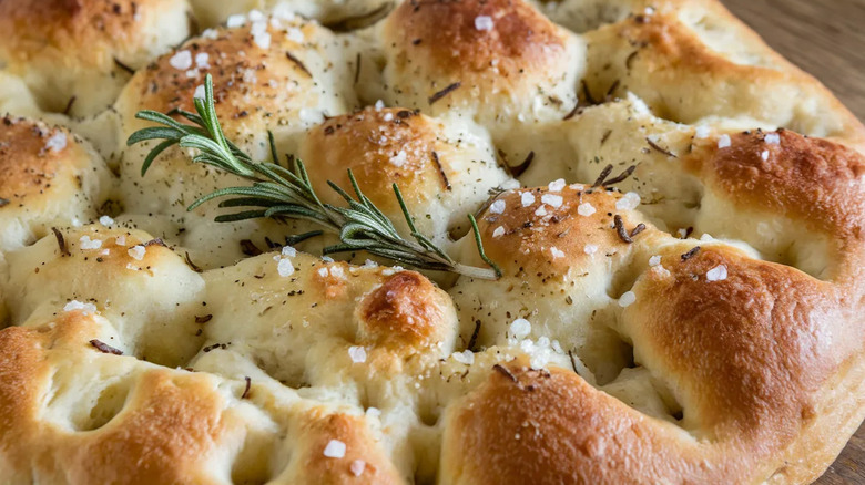 Close-up of focaccia bread, topped with coarse sea salt and rosemary