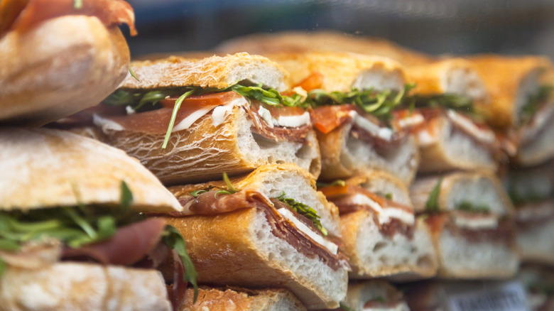 Panini sandwiches stacked behind glass.