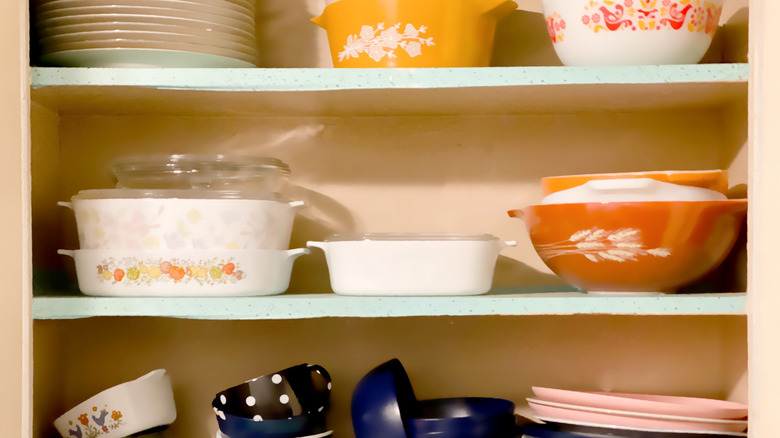 Casserole dishes and plates stacked on shelf