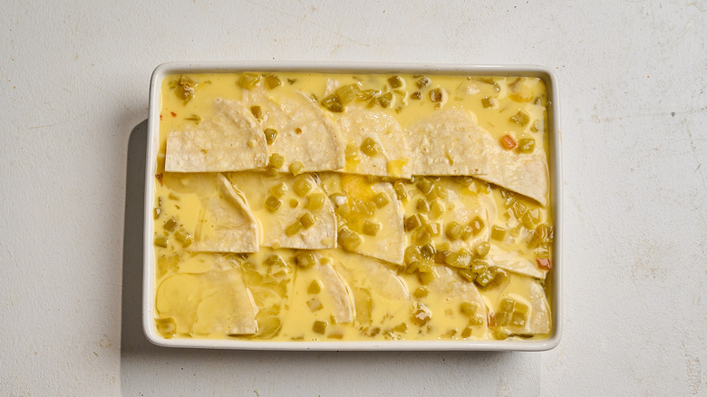 egg poured into casserole dish with tortillas
