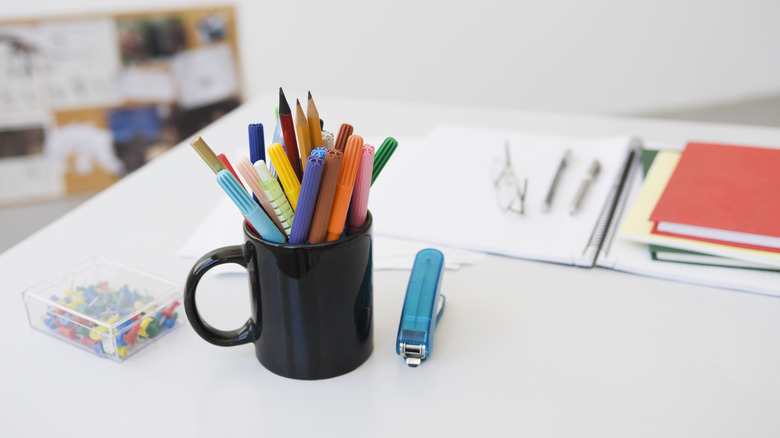 A mug holding pens and pencils on a desk